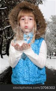 Beautiful little girl blowing snow off of her hands