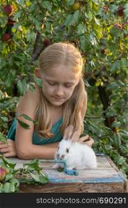 beautiful little girl holding in hands white rabbit at the garden