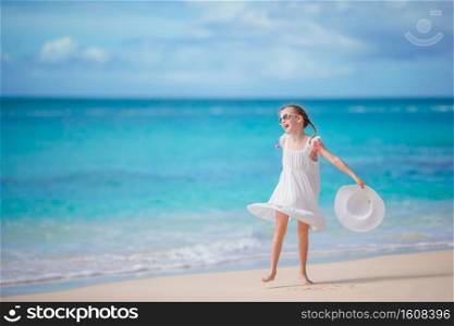 Beautiful little girl in dress at beach having fun. Happy girl enjoy summer vacation background the blue sky and turquoise water in the sea on caribbean island. Beautiful little girl in dress at beach having fun.