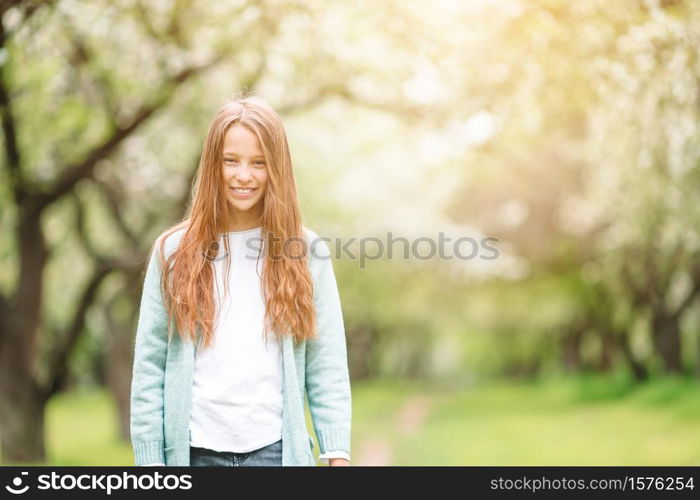 Beautiful little girl in the park outdoors. Little smiling girl playing in the park