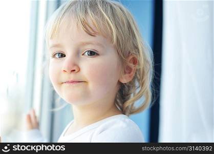 Beautiful little girl is by window portrait