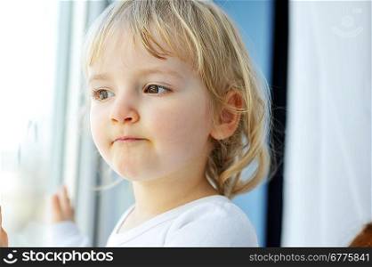 Beautiful little girl is by window portrait
