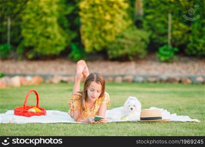 Beautiful little girl listen music and relax outdoors in the park. Little smiling girl playing in the park