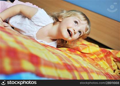 Beautiful little girl lying on bed at house