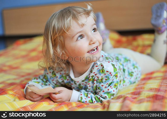 Beautiful little girl lying on bed at house