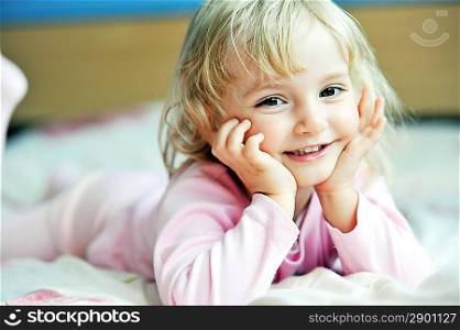 Beautiful little girl lying on bed at house