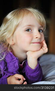 Beautiful little girl lying on bed at house