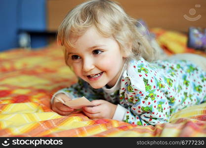 Beautiful little girl lying on bed at house