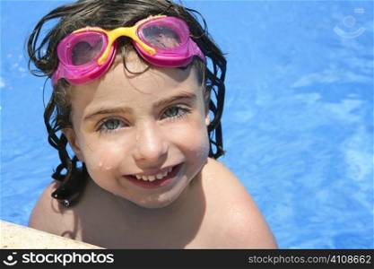 beautiful little girl smiling in blue water with pink goggles
