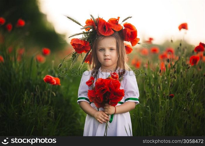 beautiful little girl with a wreath of poppies in a white dress and a bouquet of wildflowers. cute child in poppy field.. beautiful little girl with a wreath of poppies in a white dress and a bouquet of wildflowers. cute child in poppy field