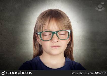 Beautiful little girl with glasses and her eyes closed on a over gray background