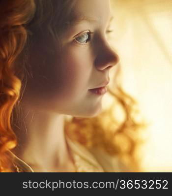 Beautiful little girl with long red curls hair