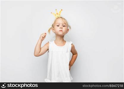 Beautiful little girl with paper crown posing on white backgroun. Beautiful little girl with paper crown posing on white background at home