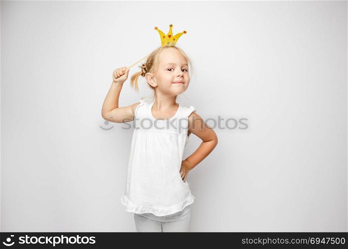 Beautiful little girl with paper crown posing on white background at home. Beautiful little girl with paper crown posing on white backgroun