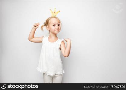 Beautiful little girl with paper crown posing on white background at home.. Beautiful little girl with paper crown posing on white background at home