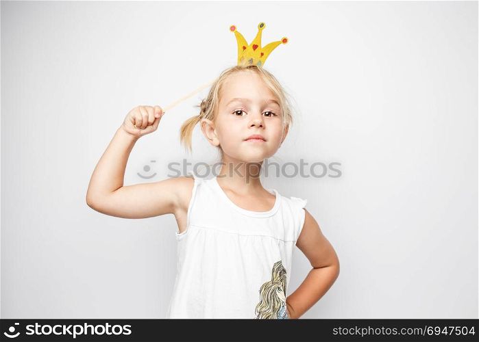 Beautiful little girl with paper crown posing on white background at home.. Beautiful little girl with paper crown posing on white background at home