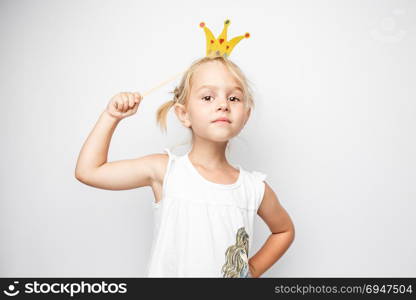 Beautiful little girl with paper crown posing on white background at home.. Beautiful little girl with paper crown posing on white background at home