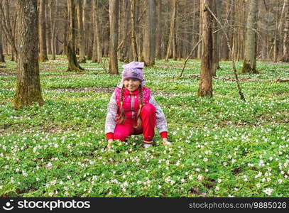 beautiful little girl with wild white flowers in forest on sunny spring day closeup