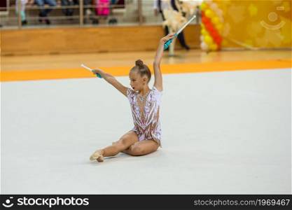 Beautiful little gymnast girl with her performance on the carpet on the competition. Beautiful little active gymnast girl with her performance on the carpet