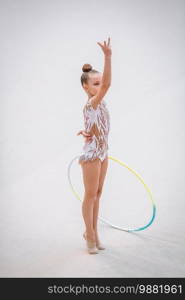 Beautiful little gymnast girl with hoop on the carpet on the competition. Little gymnast training on the carpet and ready for competitions
