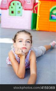 beautiful little serious girl lying on floor in playground