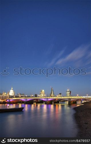 Beautiful London City skyline landscape at night with glowing ci. England, London, South Bank. View along River Thames at night of London city skyline.. Stunning London City skyline landscape at night with glowing city lights and iconic landmark buldings and locations