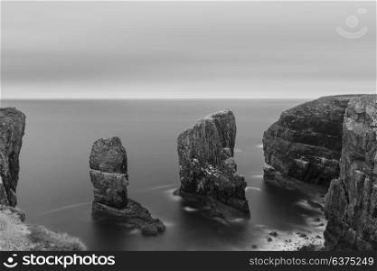 Beautiful long exposure black and white landscape image of Elegug Stacks on Pembrokeshire Coast in Wales