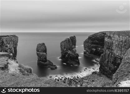 Beautiful long exposure black and white landscape image of Elegug Stacks on Pembrokeshire Coast in Wales