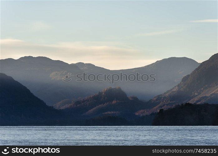Beautiful long exposure landscape image of Derwent Water in Lake District during Autumn Fall sunrise with soft pastel colors