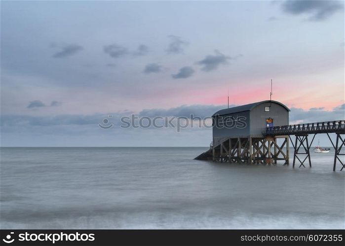 Beautiful long exposure landscape image of lifeboat jetty at sea