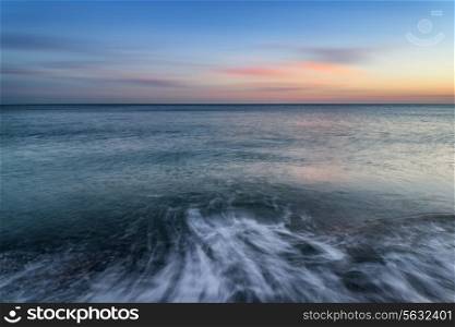 Beautiful long exposure seascape image of calm ocean at sunset