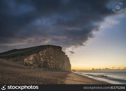 Beautiful long exposure sunrise landscape image of West Bay in Dorset England