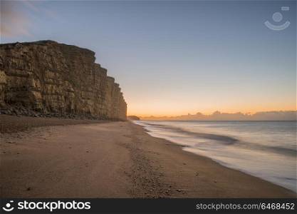 Beautiful long exposure sunrise landscape image of West Bay in Dorset England