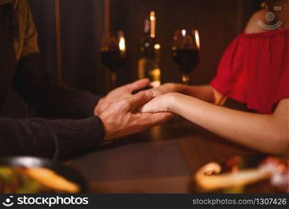 Beautiful love couple in restaurant, romantic evening. Elegant woman in red dress and her man sitting at the table, anniversary celebration. Love couple in restaurant, romantic evening