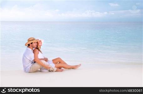 Beautiful loving couple sitting on the beach, spending honeymoon on Maldives, relaxation on summer resort, love concept