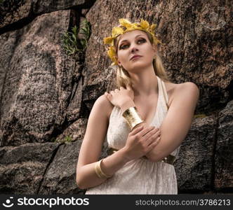 Beautiful makeup girl wearing white tunic and an antique jewels, rocky wall on background