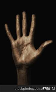 beautiful man&rsquo;s hand in golden paint on black background close up