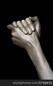 beautiful man&rsquo;s hands in bronze paint isolated on a black background