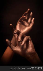 beautiful man&rsquo;s hands in bronze paint on a black background