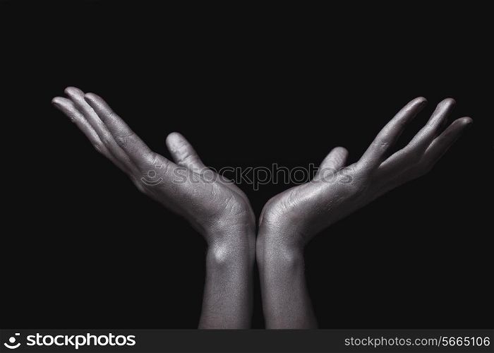 beautiful man&rsquo;s hands in silver paint on black background