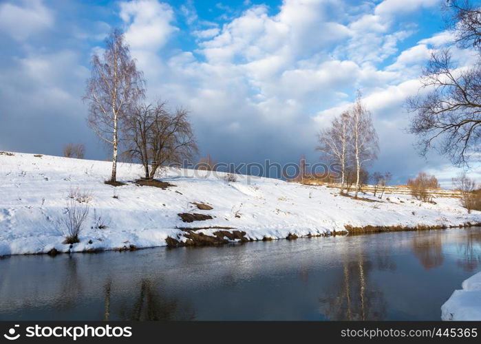 Beautiful March landscape with a small quiet river on a cloudy day.