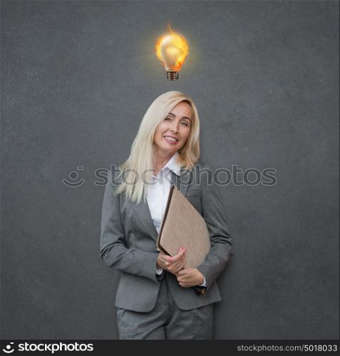 Beautiful mature business woman with idea light bulb above head on gray background