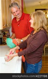 Beautiful mature couple cleaning the dishes together.