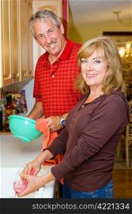Beautiful mature couple sharing the household chores, doing dishes together.