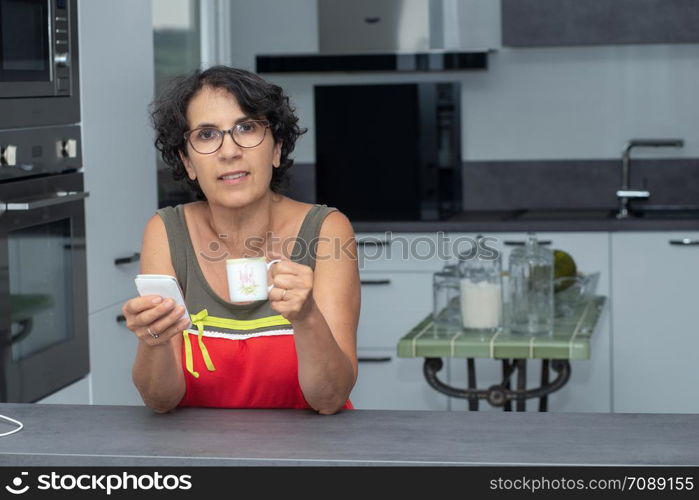 beautiful mature woman drinking coffee in the kitchen