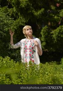 Beautiful mature woman in a garden, sunny summerday
