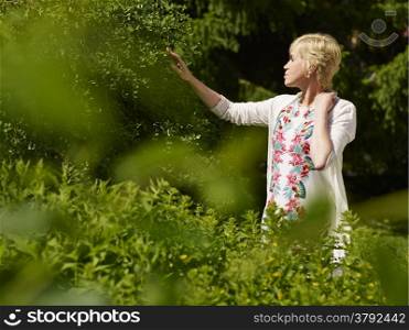 Beautiful mature woman in a garden, sunny summerday