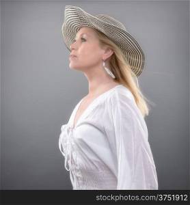 Beautiful mature woman wearing summer shirt and hat, studio shot