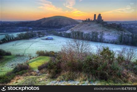 Beautiful Medieval castle ruin in countryside landscape during W. England, Dorset, Corfe Castle. Colourful sunrise over Corfe Castle.. Stunning Winter sunrise landscape over frosty Medieval castle on hill in countryside