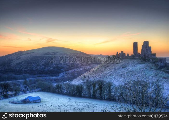 Beautiful Medieval castle ruin in countryside landscape during W. England, Dorset, Corfe Castle. Colourful sunrise over Corfe Castle.. Stunning Winter sunrise landscape over frosty Medieval castle on hill in countryside
